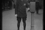 A dimanian LPD officer in a early LPD uniform stands next to a new call box.