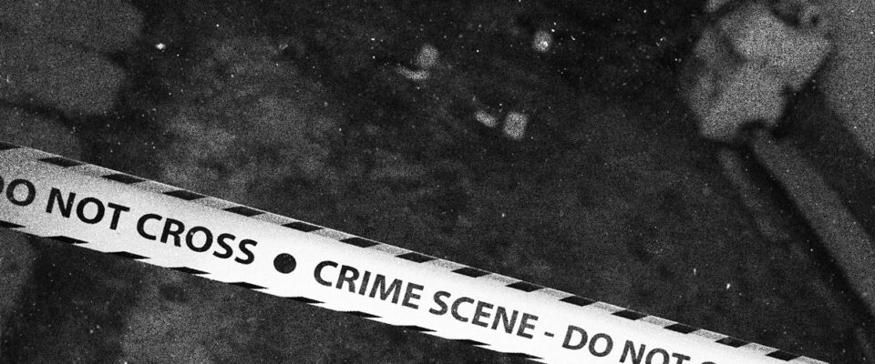 A crime scene, close up of police tape, that reads CRIME SCENE DO NOT CROSS