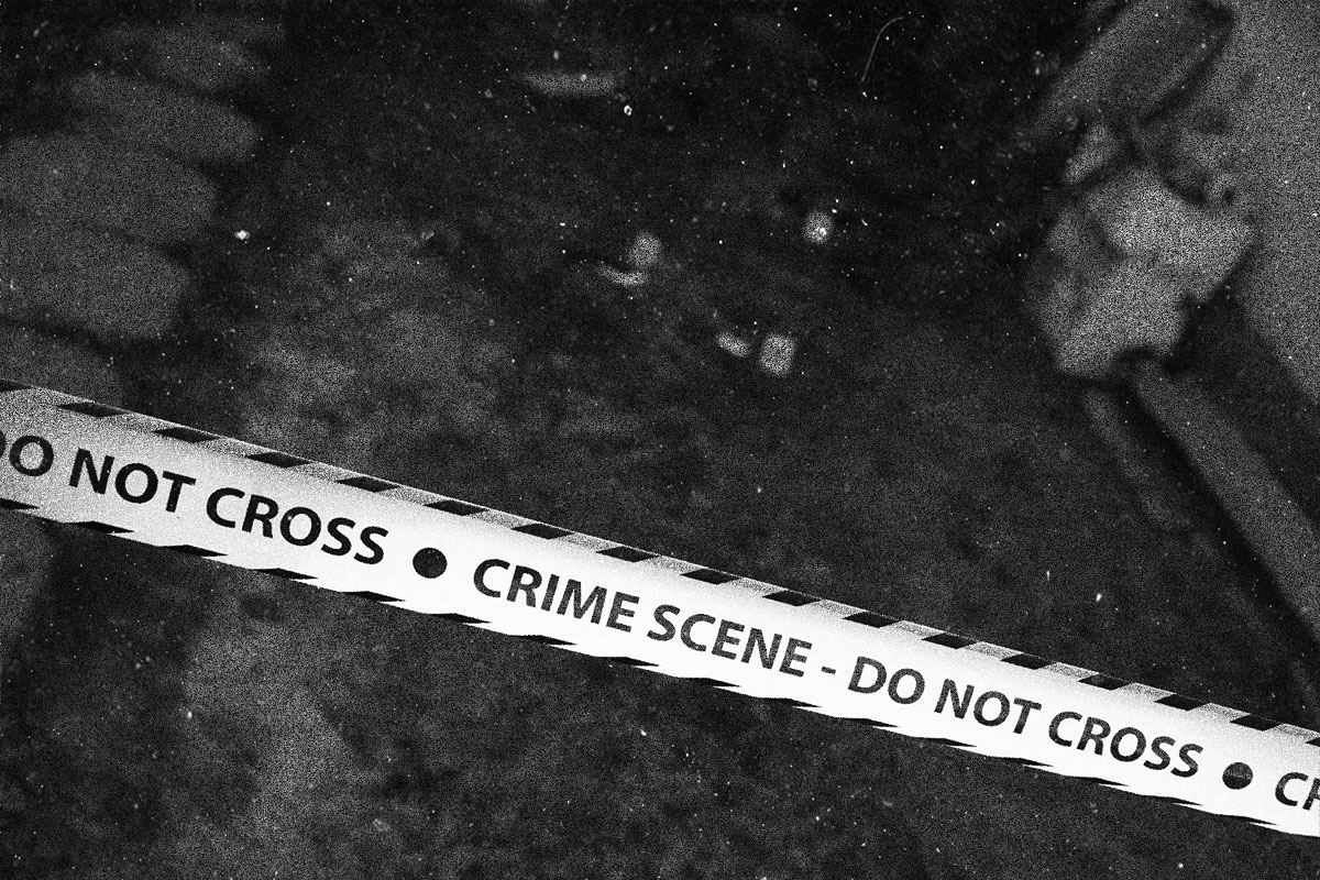 A crime scene, close up of police tape, that reads CRIME SCENE DO NOT CROSS